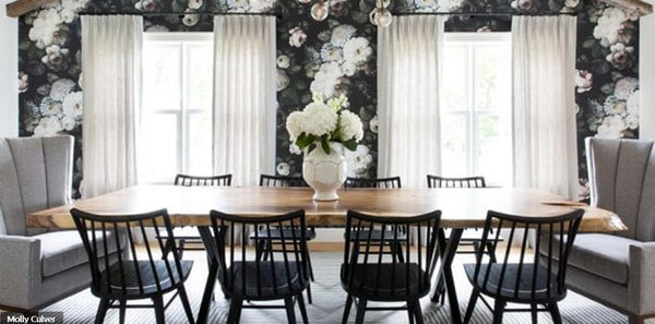 Black floral wallpaper in a modern country dining room, black and white design, black and white floral wallpaper, grey upholstered chairs, black wood   dining chairs, gray area rug, white draperies, white geometric vase, grey upholstery fabric, sheer