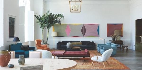Contemporary living room from Elle Decor, colorful design, color block upholstery, colorful wall art, orange rug, lantern pendant lighting, wood dining table, blue velvets, orange velvet, wood table, blue stripe upholstery fabric, white walls