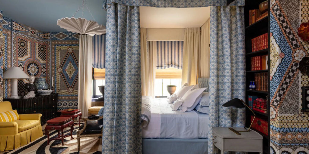 blue bedroom, canopy bed, kips bay new york showhouse 2023, mary mcdonald bedroom, geometric wallpaper, tile patterned wallpaper, neutral area rug, blue bedding, four poster bed, blue canopied bed, white bedside table, gold table lamps, yellow sofa