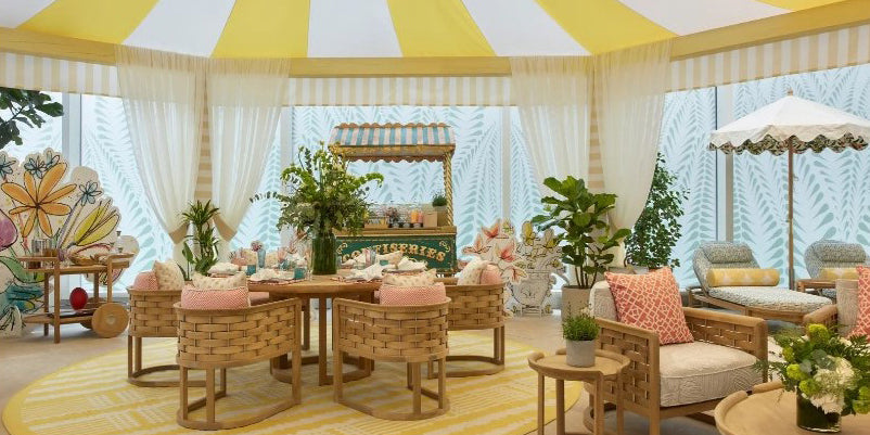 terrace design, yellow striped tent, tented room, outdoor rattan furniture, yellow round outdoor area rug, london chelsea design center terrace, yellow and pink outdoor design, outdoor living, rattan bar cart, pink throw pillows, breezy design