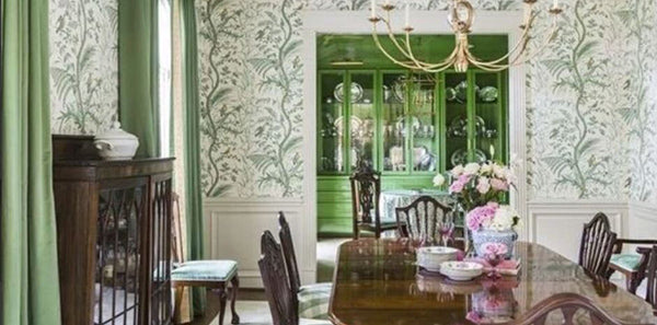 Brunschwig & Fils Bird And Thistle wallpaper, iconic wallpaper, bird patterned wallpaper, gold chandelier lighting, blue and white vase, green draperies, dark wood dining table, dark wood dining chairs, white accent decor, traditional design, rug