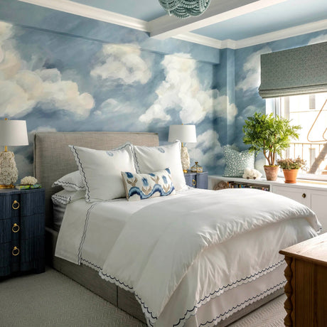 A girl'sblue  bedroom with cloud wallpaper and a double bed.