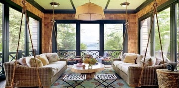 Thom Filicia's Indoor-Outdoor room, outdoor living space, lakeside country home, swinging sofas, woven sofa, natural style coffee table, earth tones, blue and red area rug, fabric pendant lighting, outdoor upholstery fabric, neutral throw pillows
