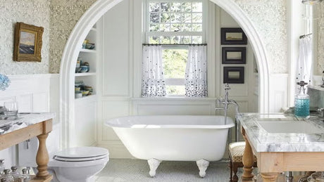 bathroom with claw foot tub; grey and beige floral wallpaper, wood vanity with a marble top