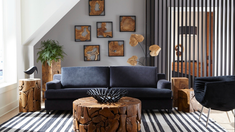 Modern family room with dark sofa, natural wood coffee table, striped rug, and abstract wood wall art in a minimalist space; Phillips Collection teak coffee tables; 