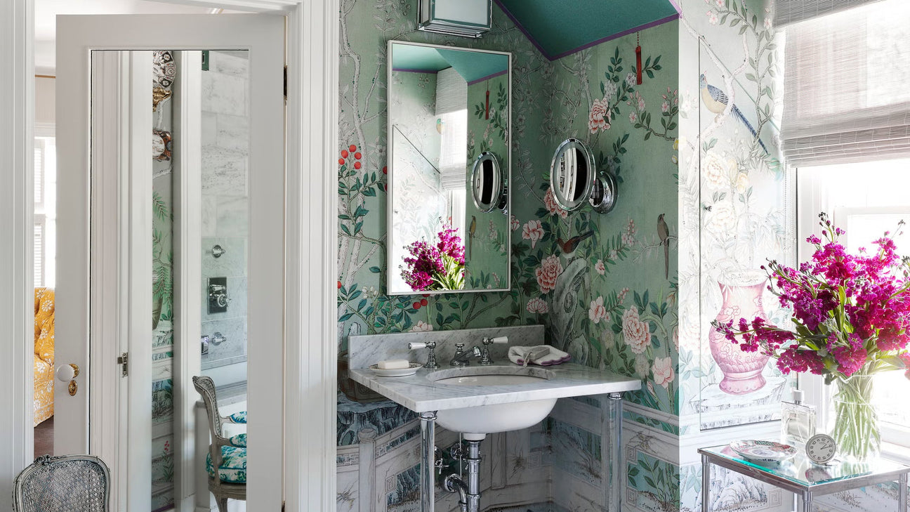 Green powder room with floral bird wallpaper, marble sink, chrome fixtures, and colorful ceiling
