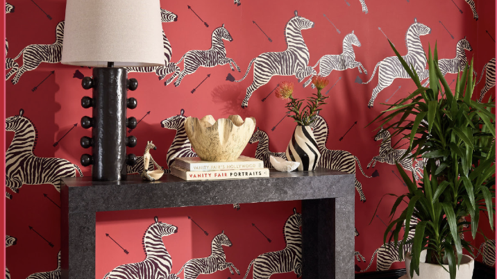 A bold entryway and foyer with red zebra wallpaper and a black parson table console; sclaamndre red zebras wallpaper