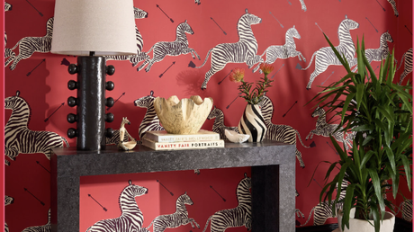 A bold entryway and foyer with red zebra wallpaper and a black parson table console; sclaamndre red zebras wallpaper