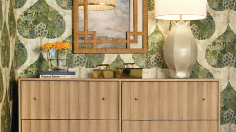 a contemporary foyer with a large laeaf patterned wallpaper and rattan sideboard. 