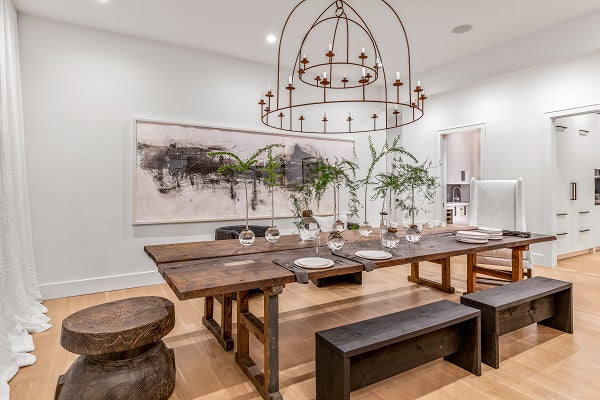 Lukas Machnik, large brass chandelier lighting, rustic dining room table, rustic bench, rustic stool, large wall art, white draperies, white walls, white upholstered chair, glass vases, minimalist design, chic design, good design, holiday house