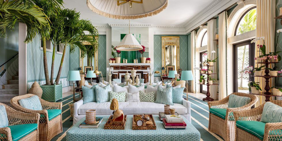 aqua living room, rattan furniture, amanda lindroth kips bay palm beach showhouse, coastal design, blue throw pillows, pendant lighting, wood framed mirrors, blue and white striped area rug, wood plant shelf, blue coffee table, blue diamond wallpaper