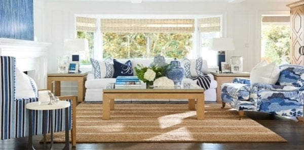 Blue & White Living Room by Barclay Butera in The Hamptons, tan area rug, blue stripe fabric, earthy tones, wood coffee table, asian inspired upholstery, blue and white design, striped rug, blue table lamps, wood side tables, blue art, blue pillows