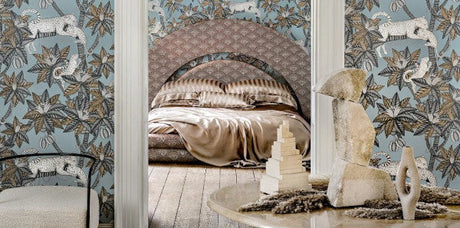 travel-inspired decor bedroom, travel-inspired wallpaper pattern, cole & son ardmore-jabula, Brewster Seychelles, York Mediterranean, travel-inspired interior design, blue exotic wallpaper pattern, golden bedding, dark tan upholstered headboard