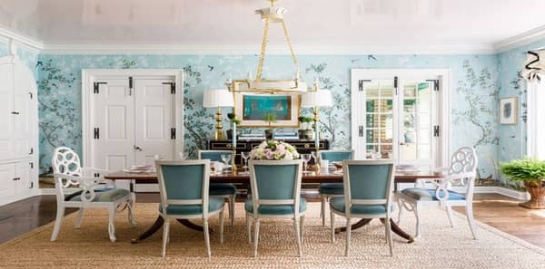aqua wallpaper, chinoiserie wallpaper, paloma contreras, lake shore showhouse, mural wallpaper, blue floral mural, white and blue dining room chairs, rattan area rug, textured rug, white wooden chairs, gold chandelier lighting, gold table lamps