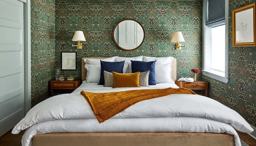 green bedroom, green floral wallpaper, Morris Blackthorn DMY1BT101, william morris, maximalist bedroom, fresh maximalism, maximalist wallpaper, blue and gold throw pillows, wood framed mirror, gold throw blanket, wood bedside tables, gold sconces