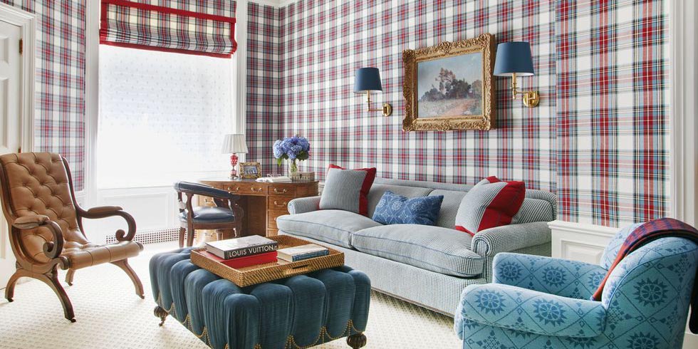red plaid wallpaper, blue upholstered chair, blue upholstered ottoman, leather chair, plaid drapery, matching wallpaper and fabric, white area rug, blue gold sconce lighting, wood desk, red and blue throw pillows, red and blue design, plaid design