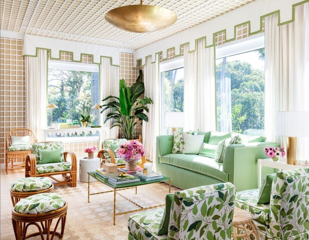 Sun room, porch, Palm Beach Kips Bay 2022, Paloma cContreras, green foliage fabric on rattan furniture, lattice walls, beige walls, green upholstered outdoor sofa, outdoor living, woven chairs, foliage fabric pattern, white throw pillows, white drape