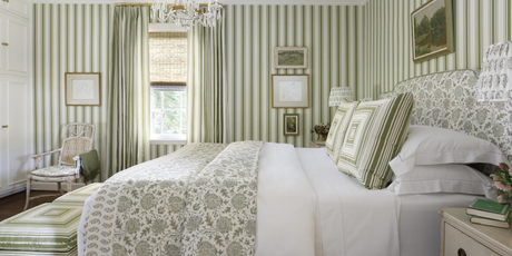 green stripe wallpaper, green stripe drapery, coordinating wallpaper and fabric, green floral bedding, green striped pillows, green striped stools, wall art, glass pendant lighting, rattan chair, ikat fabric, upholstered headboard, green blanket