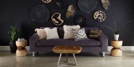 living room with organic style side tables, phillips collection side tables, dark toned design, earthy living room, exotic throw pillows, organic wood slab coffee table, dark upholstered sofa, organic wood wall art, earth tone living room, side table