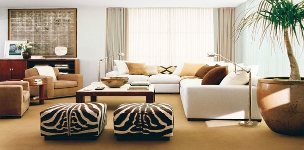Living room with white sofa and zebra ottomans by Ralph Lauren, animal print upholstery fabric, tan area rug, neutral drapery, brown sueded velvet upholstery fabric, zebra print ottomans, textured throw pillows, brown pillows, sisal rug, club chairs
