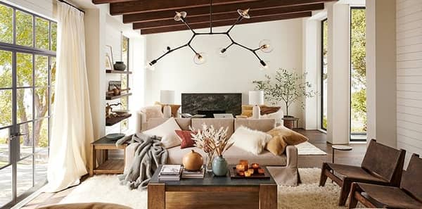 country living room, earth tones living room, earth tone designer fabric and decor, textured white area rug, wood accent decor, abstract pendant lighting, white draperies, earth tone throw pillows, earth tone interior design, grey throw blanket