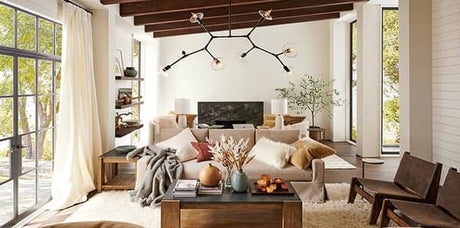 country living room, earth tones living room, earth tone designer fabric and decor, textured white area rug, wood accent decor, abstract pendant lighting, white draperies, earth tone throw pillows, earth tone interior design, grey throw blanket
