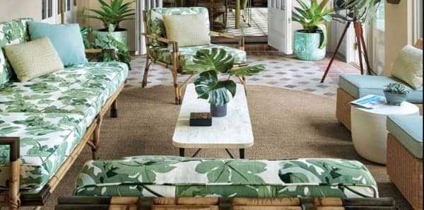 porch with rattan furniture, tropical leaf fabric pattern, outdoor fabric, green leaf fabric, tropical porch design, rattan chairs, green outdoor upholstery fabric, beige textured area rug, white coffee table, beige throw pillows, outdoor living