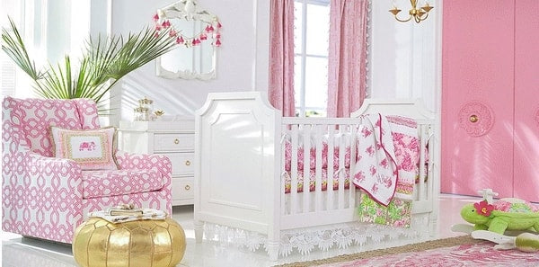 pink and white nursery, white crib with pink bedding, pink walls, pink drapery fabric, pink and white area rug, nursery, nursery design, pink and white design, gold pendant lighting, white framed mirror, pink and white geometric upholstered chair