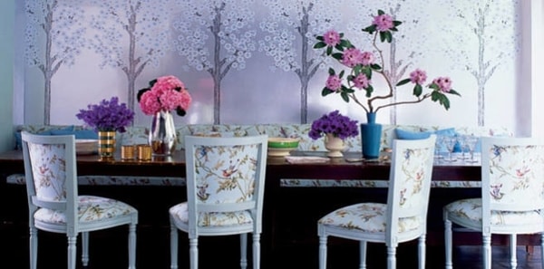 dining room with cole and son hummingbird fabric, mural wallpaper, natural design mural, pink and white dining room, dark wood dining table, white dining chairs, gold accent decor, mirrored vase, pink and white design, feminine design, blue pillows
