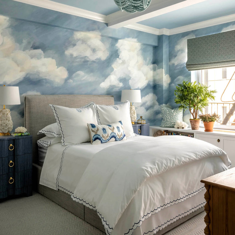 Serene bedroom with blue sky cloud wallpaper, white bedding, upholstered bed, soft lighting, and natural light from window; Corey Damin Jenkins kids room