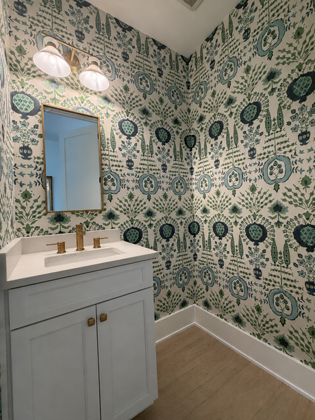 Bathroom with patterned wallpaper, sink, and mirror.