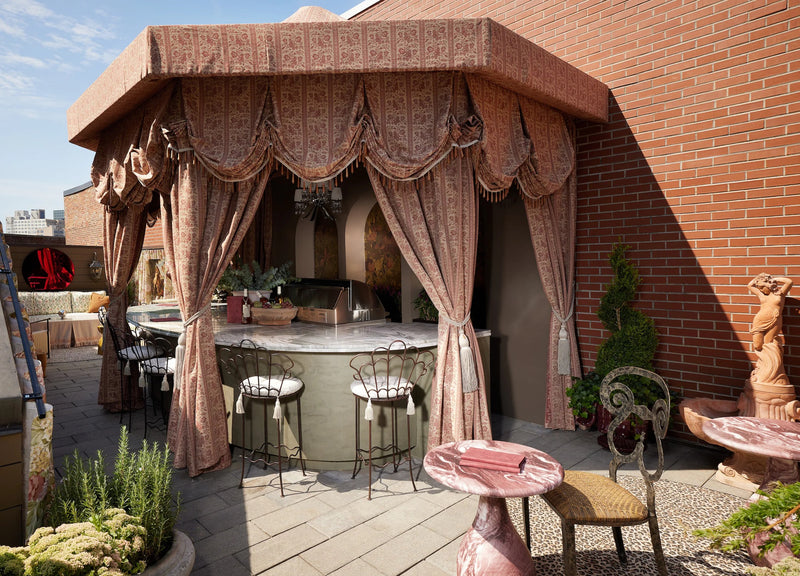 Rooftop terrace by Nicole Fisher at the Kips Bay NYC Show House, featuring a blush floral canopy, tasseled drapery, curved bar and pink marble tables.