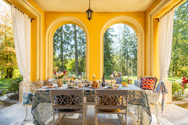 summer alfresco dining in a yellow loggis; arched loggia with dining table